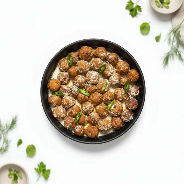 Dish of meatballs with green herbs on a dark background, branded 'Tazweed'.